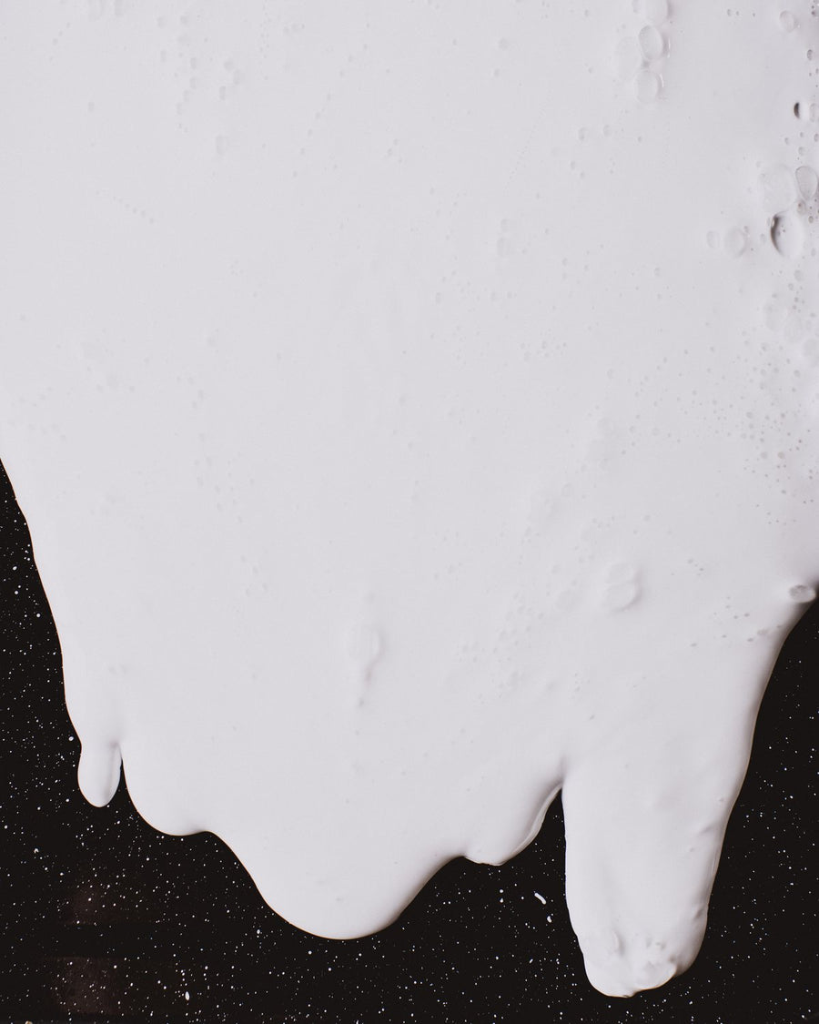 Thick white milk pouring over a dark surface
